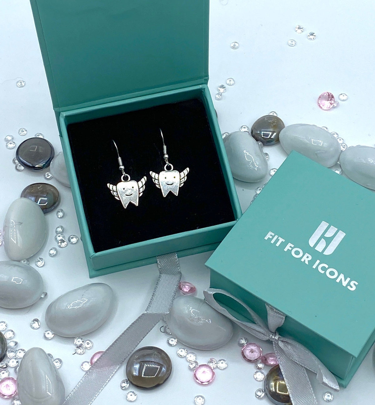 Silver coloured earrings in a tooth shaped design with wings attached to look like a tooth fairy. 