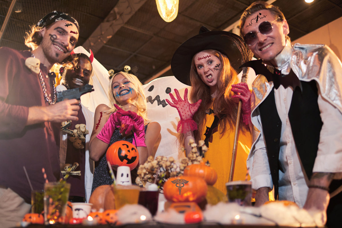 Group of men and women dressed in halloween outfits and drinking from skull shaped shot glasses