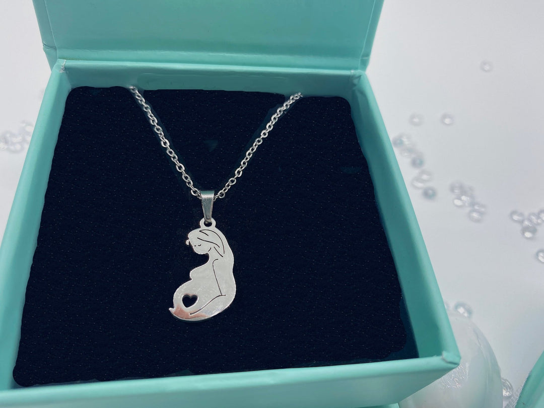 A silver necklace featuring a pendant shaped like a baby in the uterus, designed to celebrate pregnancy and motherhood.